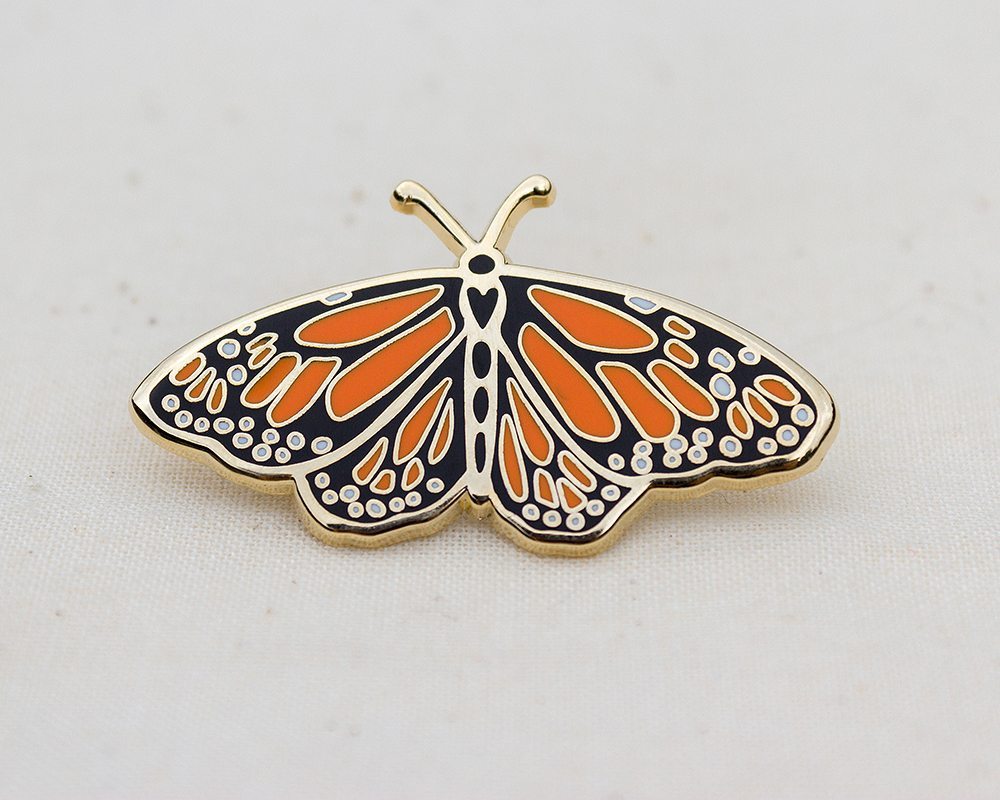 a gold enamel lapel pin of an orange and black monarch butterfly