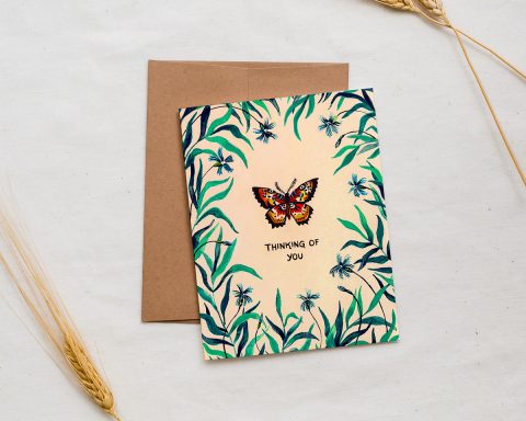 illustrated greeting card with a butterfly surrounded by foliage and text that says thinking of you