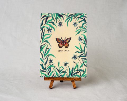 wildship studio art print of garden butterfly with green foliage and blue flowers on a small wooden easel