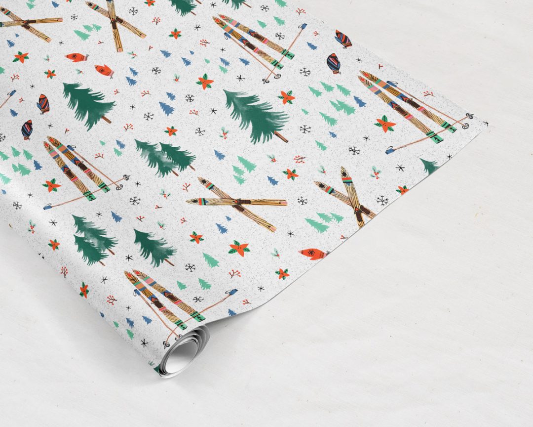 Wildship Studio holiday gift wrapping paper with vintage wooden skis, pine trees, snowflakes, poinsettia, and mistletoe