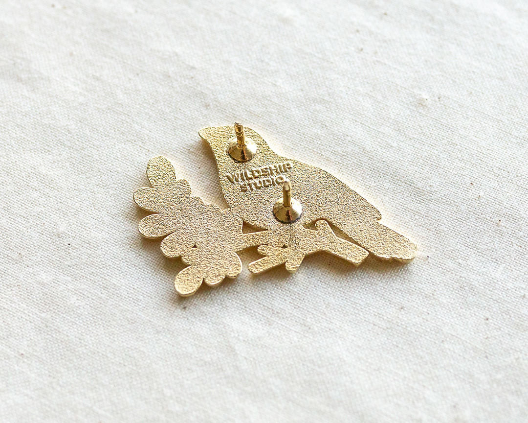 the backside of gold robin enamel pin