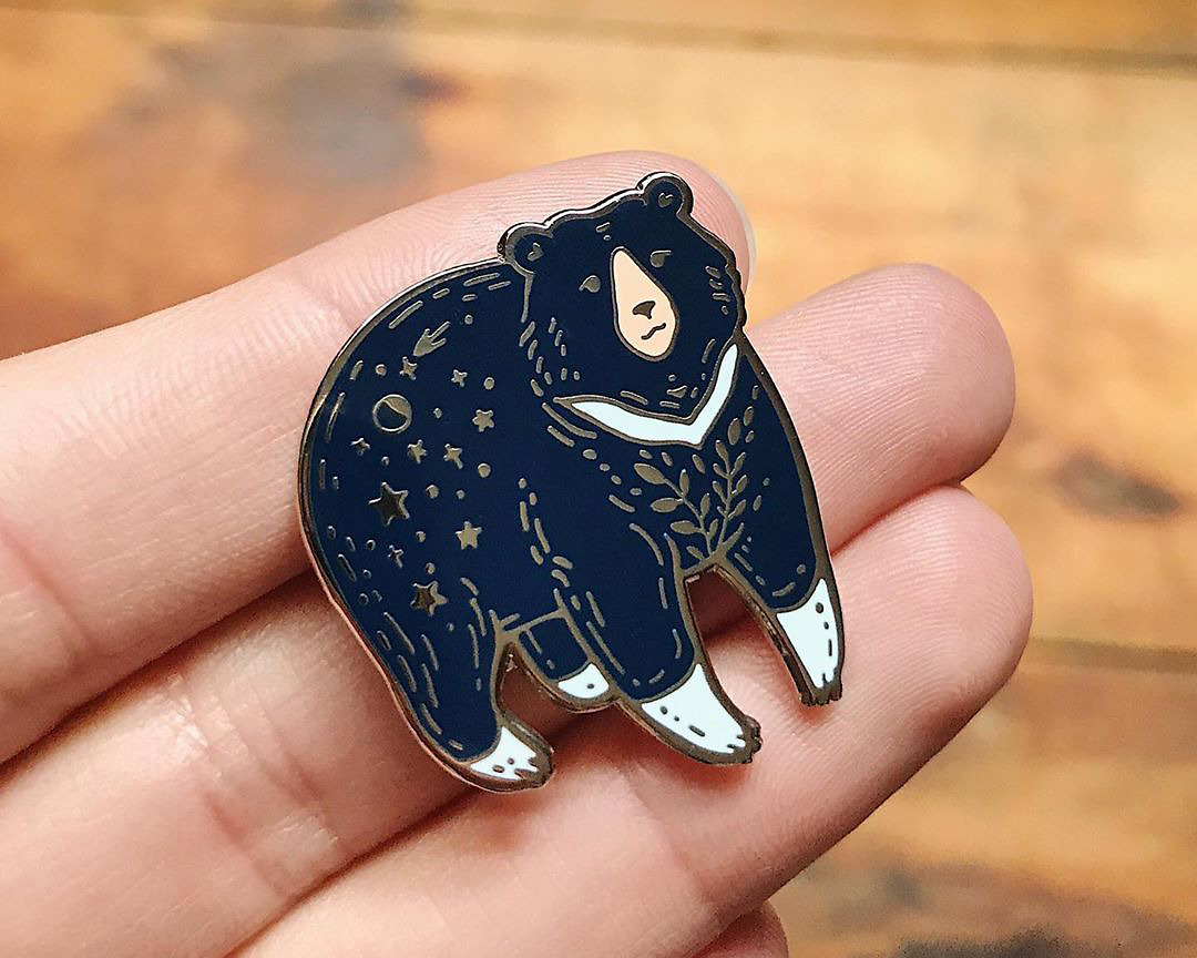 moon bear enamel pin by wildship studio held in hand