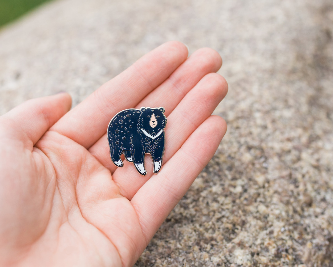 moon bear enamel pin held in palm of hand by wildship studio