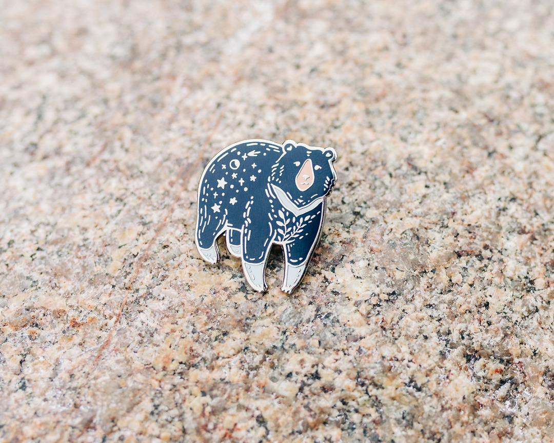 moon bear enamel pin on a rock by wildship studio