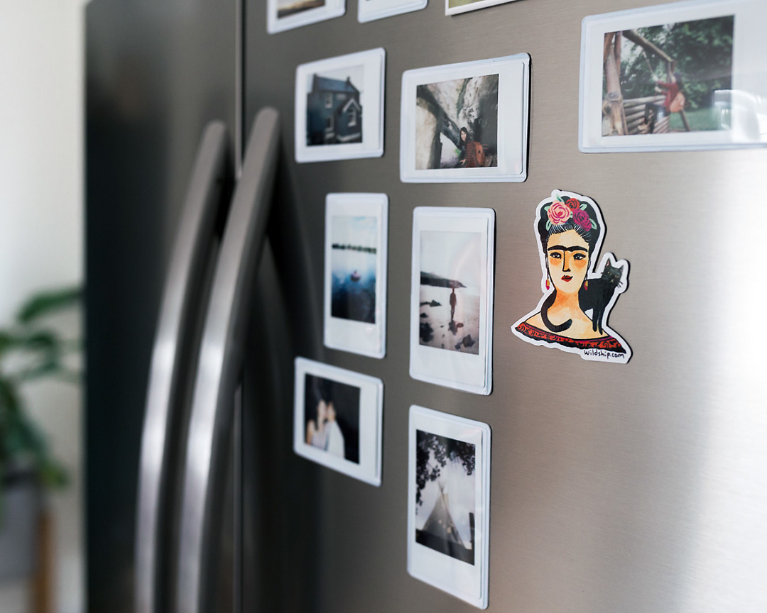 Frida Kahlo fridge magnet on stainless steel refrigerator with other photo magnets
